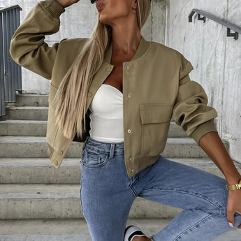 Beige cropped puffer jacket for women, featuring a casual fashion design with long sleeves and a high neck. The outerwear is paired with jeans, and the model is accessorized with sunglasses.