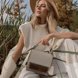 Beige designer crossbody bag displayed against a white background, showcasing its elegant design and small size, suitable for women's fashion.