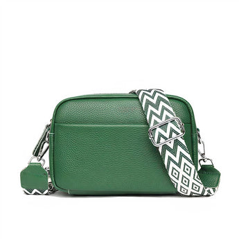 Black leather crossbody bag with a designer geometric strap, featuring an emerald green color and a rectangular shape. The handbag is a fashionable accessory with metal accents, suitable for carrying personal items.