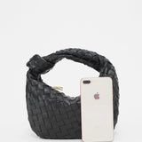 Black leather geometric woven handbag with a braided design, featuring a rectangular shape and shoulder strap, suitable as a fashionable accessory.