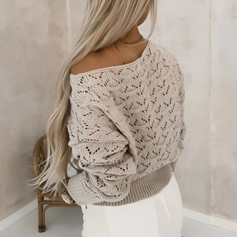 Bohemian off-shoulder crochet sweater in grey, featuring a stylish fall fashion design. The sweater showcases exposed shoulders, long sleeves, and a textured knit pattern, perfect for accentuating a woman's neck and waist. The model has long hair, complementing the chic and relaxed bohemian look.