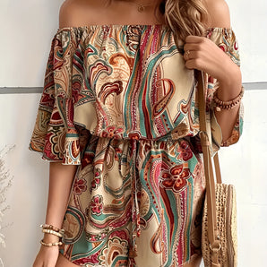 Bohemian Paisley Off-Shoulder Romper worn by a woman, showcasing a chic summer outfit with a white base and vibrant paisley pattern, featuring off-shoulder design and one-piece style, surrounded by lush greenery.