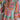 Bohemian patterned tiered midi dress featuring a pastel ethnic print, with long sleeves and a relaxed fit. The dress has a round neckline and a defined waist, showcasing a mix of pink and complementary colors.