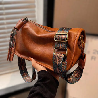 A stylish brown boho leather handbag with artisan embroidery, designed as a crossbody bag, featuring intricate patterns and a fashionable look.