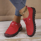 
A pair of stylish women's casual loafers with a red leather finish and decorative chain detail, set against a denim background.