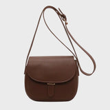 Brown leather crossbody saddle bag for women with a minimalist design, featuring a long adjustable strap and metal accents.