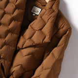 Brown quilted puffer jacket for men with a lightweight insulated design, featuring long sleeves and a high collar. The jacket is styled with khaki pants, complementing the beige tones of the outerwear.