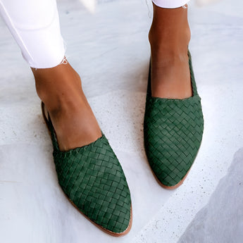 Women's green woven leather loafers with a stylish slip-on design, shown on a model's foot.