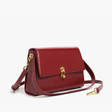 Burgundy leather handbag with a golden clasp, featuring a rectangular shape, designed as an elegant fashion accessory.