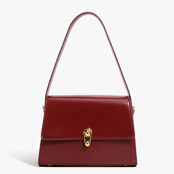 Burgundy leather handbag with a golden clasp, featuring a rectangular shape, designed for elegance and style as a shoulder or hand-held accessory.