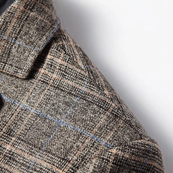 A stylish men's herringbone wool tweed blazer in grey, featuring a tailored fit perfect for winter office wear. The blazer showcases a classic plaid pattern with a structured collar and long sleeves, highlighting the fine woolen textile craftsmanship.