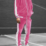 Man wearing a luxury blue velvet tracksuit and pink sneakers, standing on asphalt; the tracksuit includes a stylish jacket and pants, designed for men's sportswear.