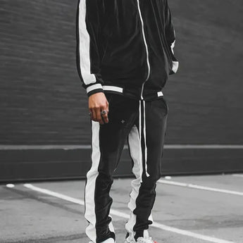 A man wearing a luxury blue velvet tracksuit, designed for men’s sportswear, standing on asphalt.