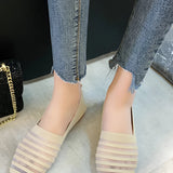 Women's white striped flats paired with chained ankle jeans, showcasing a casual denim style.