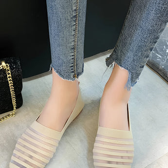 Women's white striped flats paired with chained ankle jeans, showcasing a casual denim style.