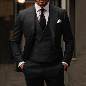 A man wearing a stylish double-breasted charcoal slim-fit suit with matching trousers, a white dress shirt, and a black tie, posed against a plain background.