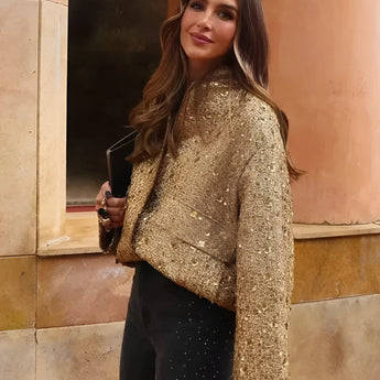 
Woman wearing a textured gold metallic bomber jacket with a chic design, featuring ribbed cuffs and hem, a full-length zipper, and a high collar. The jacket is styled as part of a fashionable outfit, highlighting its unique texture and metallic sheen.