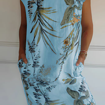 Women's summer shift dress featuring a white botanical print with tropical floral patterns, shown in the Azzurro color variant. The dress is styled as a one-piece garment, highlighting shoulder and arm coverage and suitable for a casual summer look. The garment is available in size 3XL.