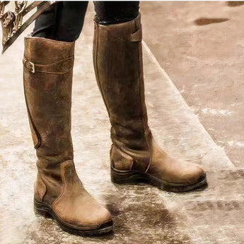 Brown women's knee-high waterproof leather equestrian riding boots displayed against a wooden background, showcasing their durable design and stylish appeal for outdoor activities.