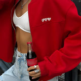 Women's white cropped bomber jacket with heart embellishments, displayed on a red XL variant. The jacket features long sleeves and a casual chic style, suitable for various occasions.