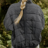 Women's lightweight insulated forest green quilted jacket with long sleeves, depicted outdoors in a natural setting.